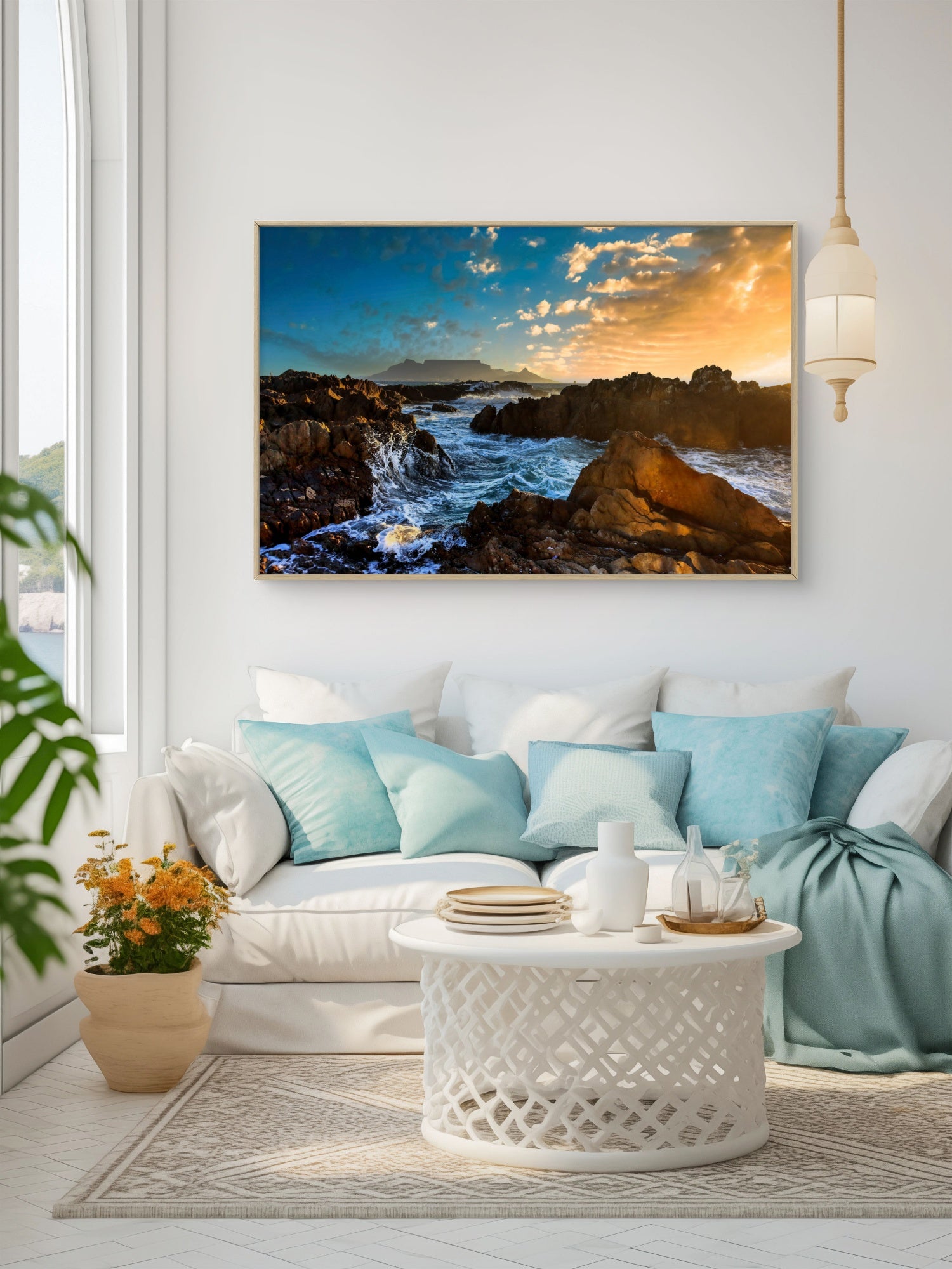 Living room with a white sofa, decorative pillows, and a large framed picture of a coastal scene on the wall.