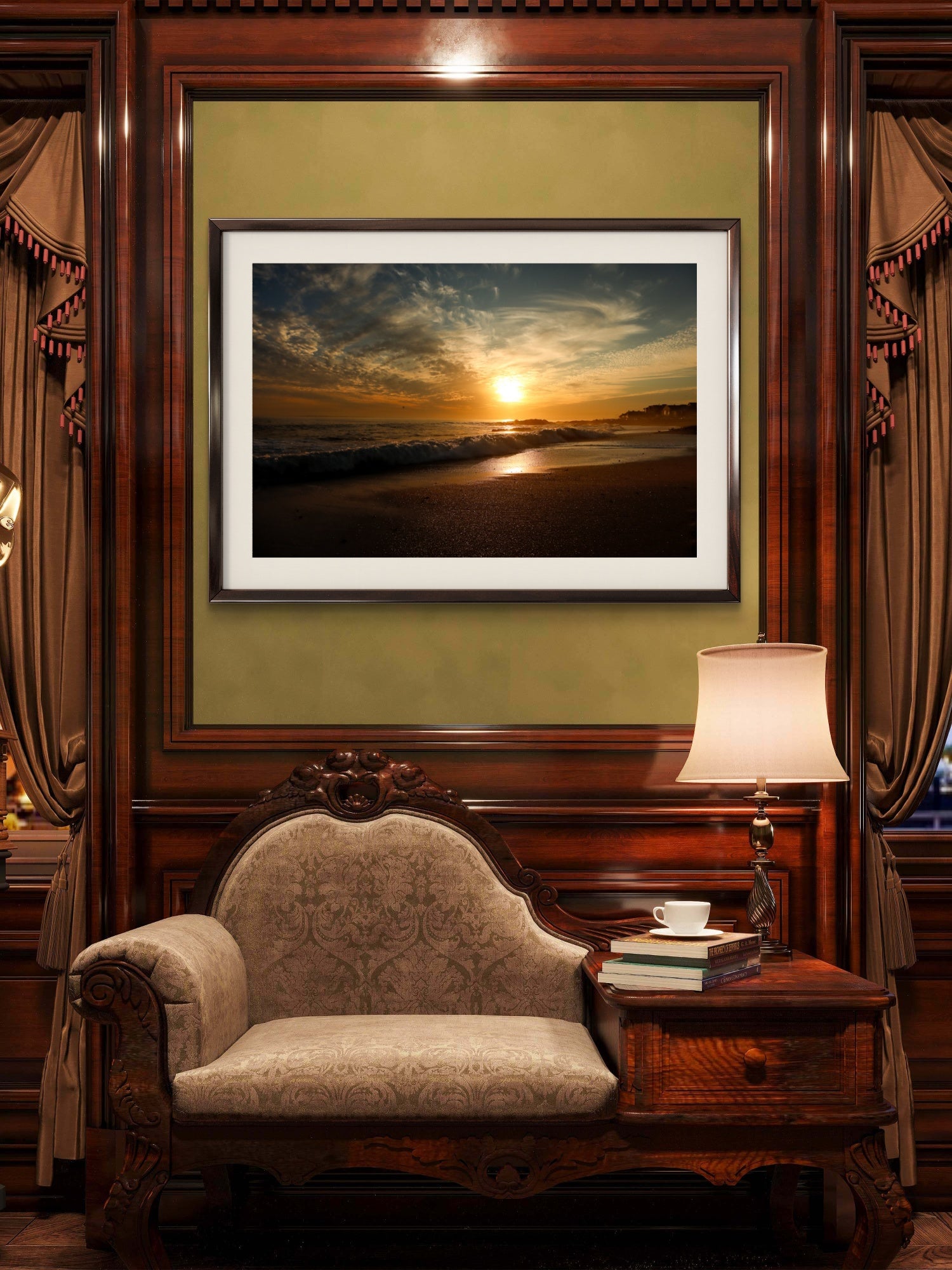 Framed beach sunset print on a wall above an ornate chair in a room with a lamp and books.