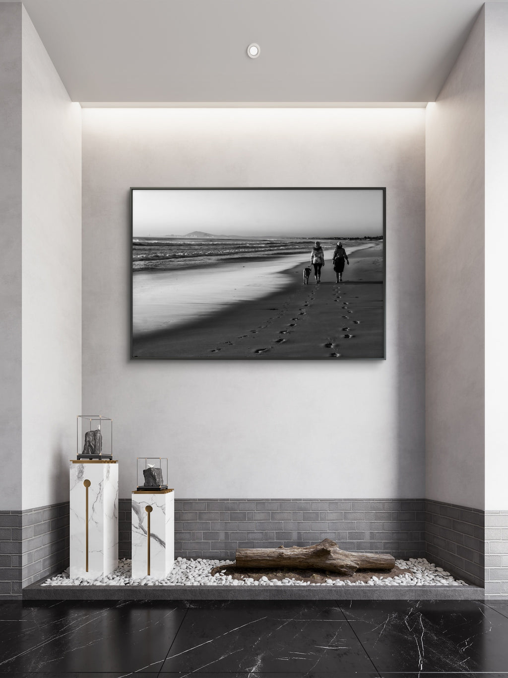 Framed black and white artwork of a beach scene with people and a dog, displayed on a wall in a modern interior setting.