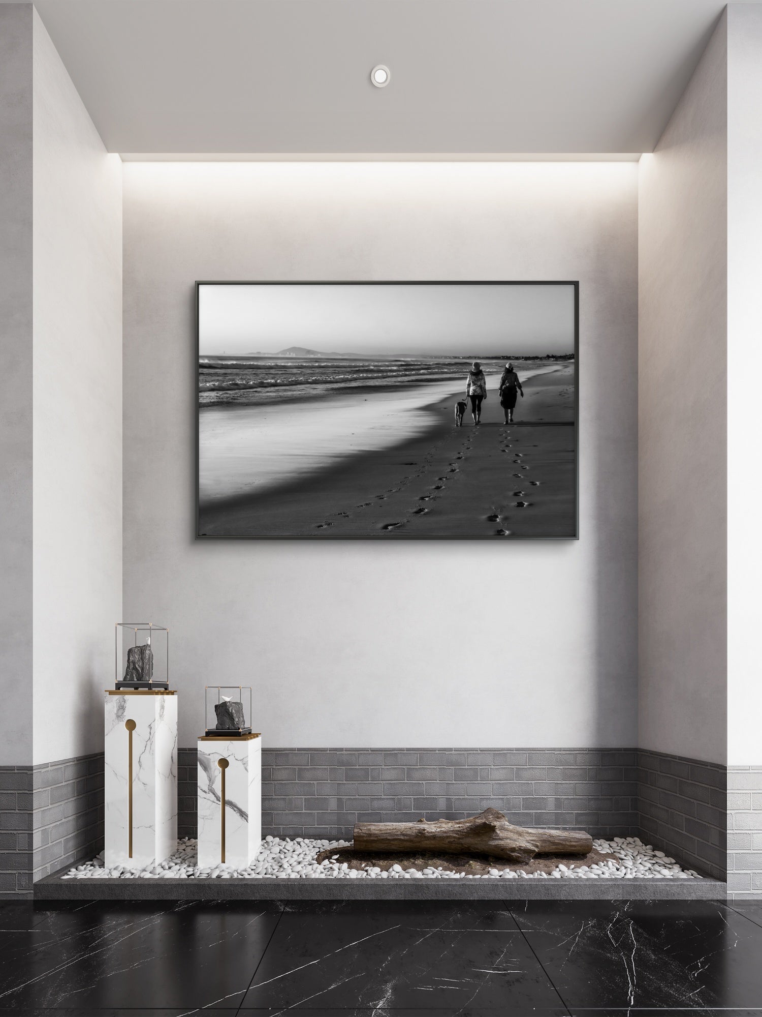 Framed black and white artwork of a beach scene with people and a dog, displayed on a wall in a modern interior setting.