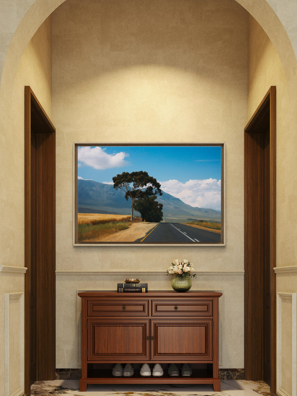 Framed landscape painting above a wooden cabinet in a room with arches.