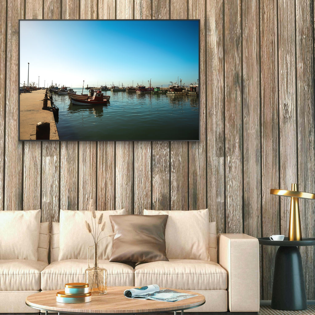 Living room with a large wall-mounted TV displaying a harbor scene, beige sofa, and wooden coffee table.