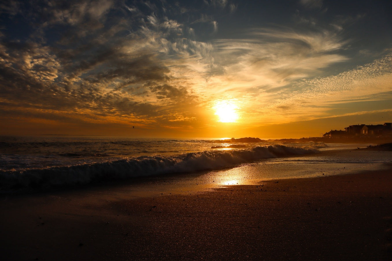 Sunset over a beach with waves crashing onto the shore