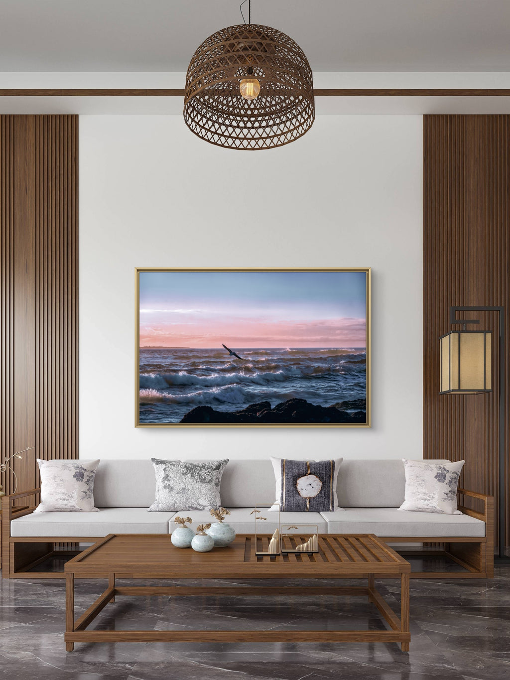 Modern living room with a sofa, coffee table, and wall art depicting a sunset over water.