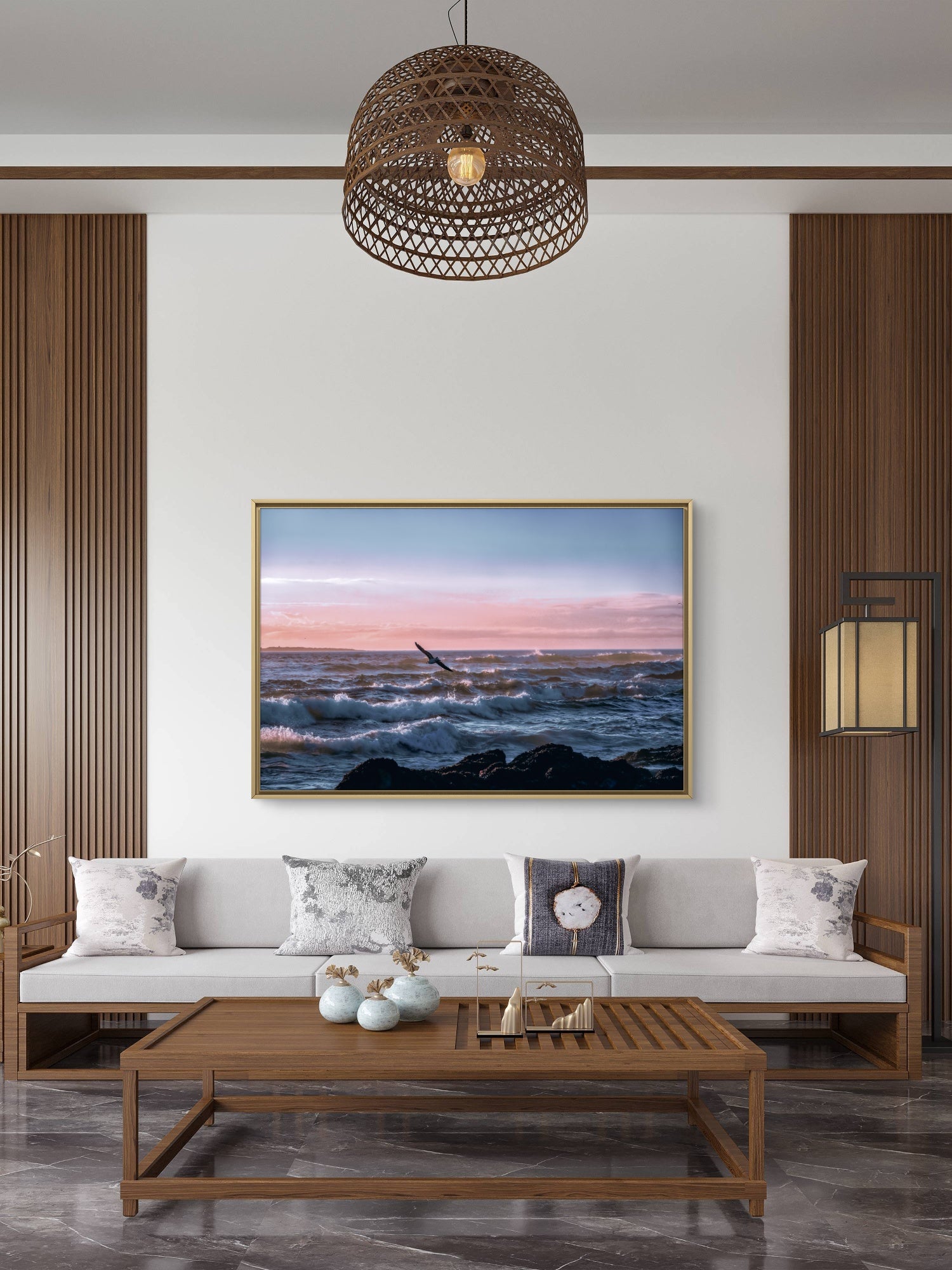 Modern living room with a sofa, coffee table, and wall art depicting a sunset over water.