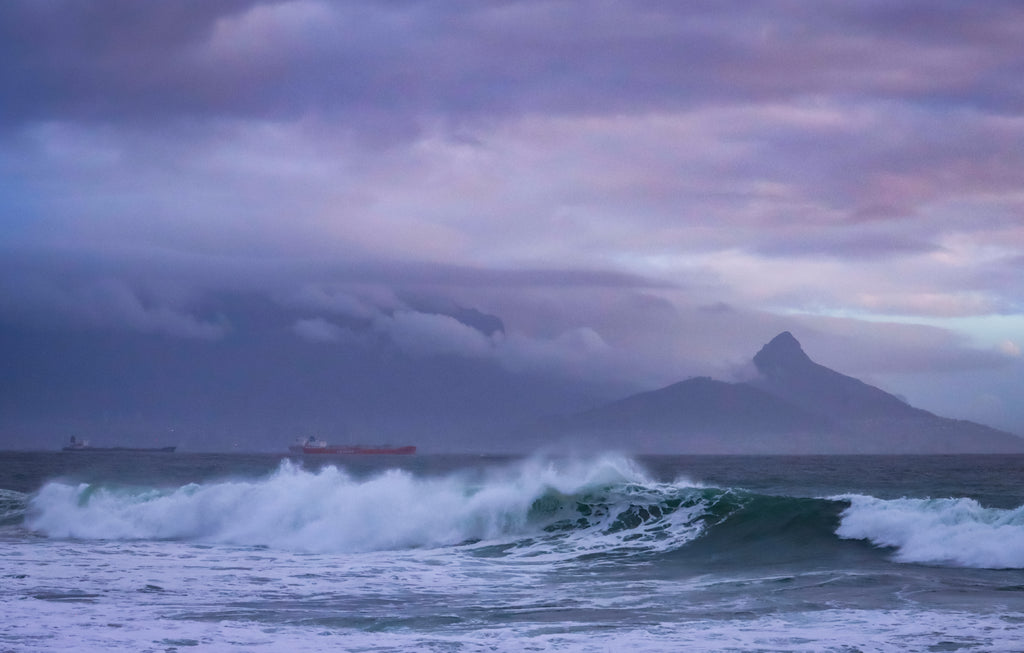 Fine art photograph of dramatic storm swells breaking on the Cape Town coast with Lion's Head silhouetted under a purple and mauve storm sky. Photography Wall Art Print.