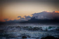 Fine art photograph of Table Mountain shrouded in storm cloud at dusk with dark Atlantic swells and amber sky over Table Bay, Cape Town South Africa seascape wall art print, ApertureAndArt.