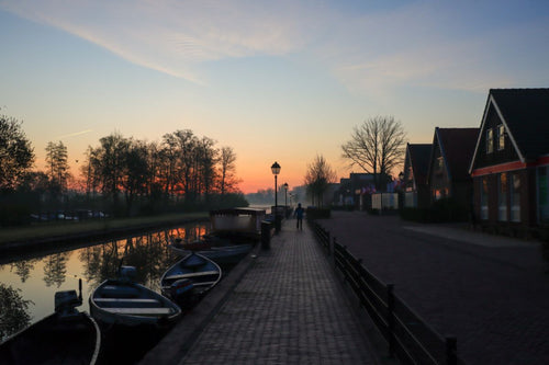 Misty sunrise over Giethoorn canal landscape with silhouetted trees reflected in calm water during early morning light in the Netherlands.