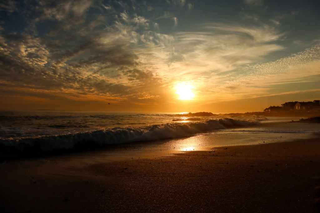 Golden sunset over Bloubergstrand with rolling ocean waves and glowing reflections along the shoreline on South Africa’s west coast.