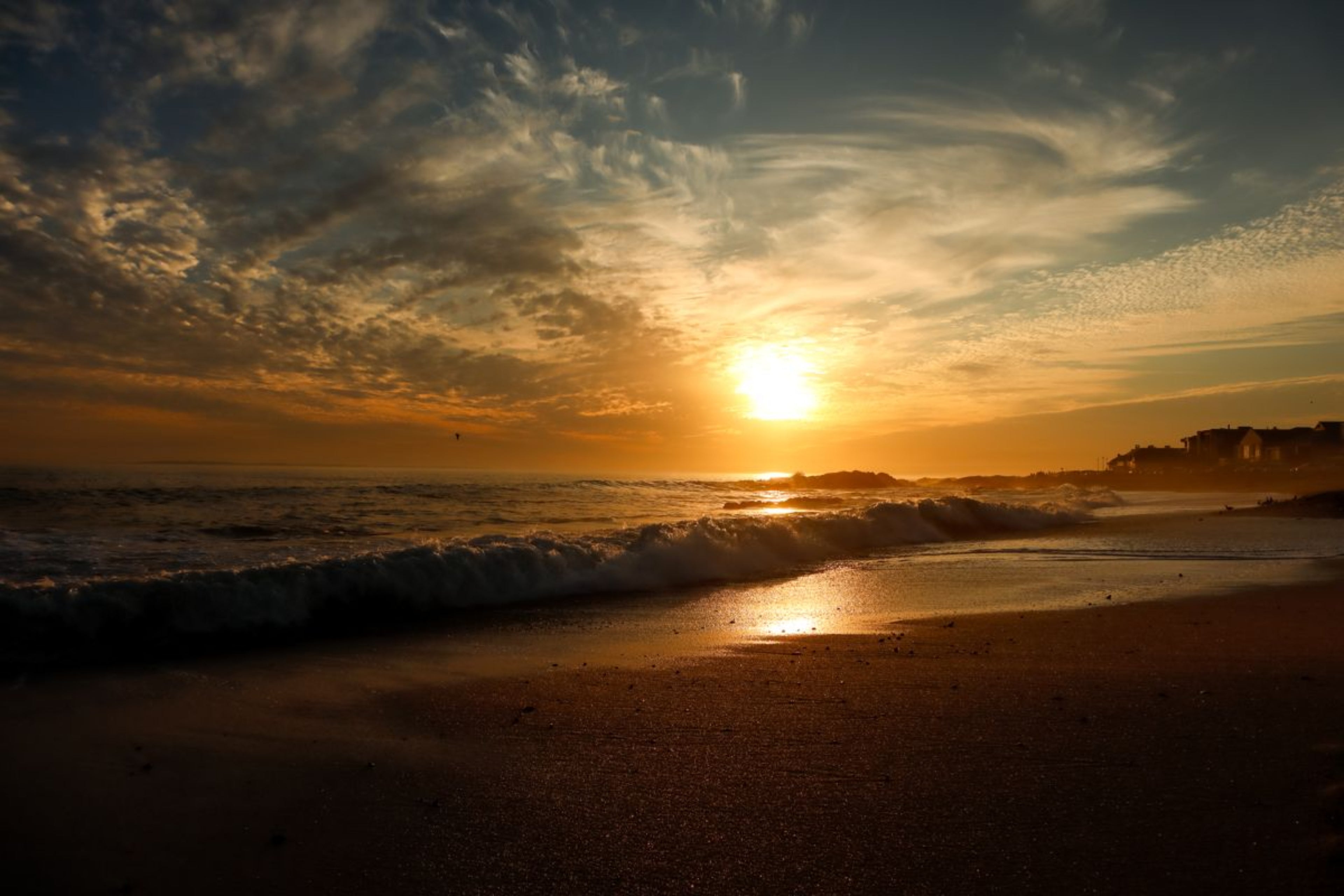 Golden sunset over Bloubergstrand with rolling ocean waves and glowing reflections along the shoreline on South Africa’s west coast.