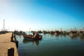 Colourful harbour boats reflected in calm blue water creating a peaceful coastal marina scene under clear daylight.