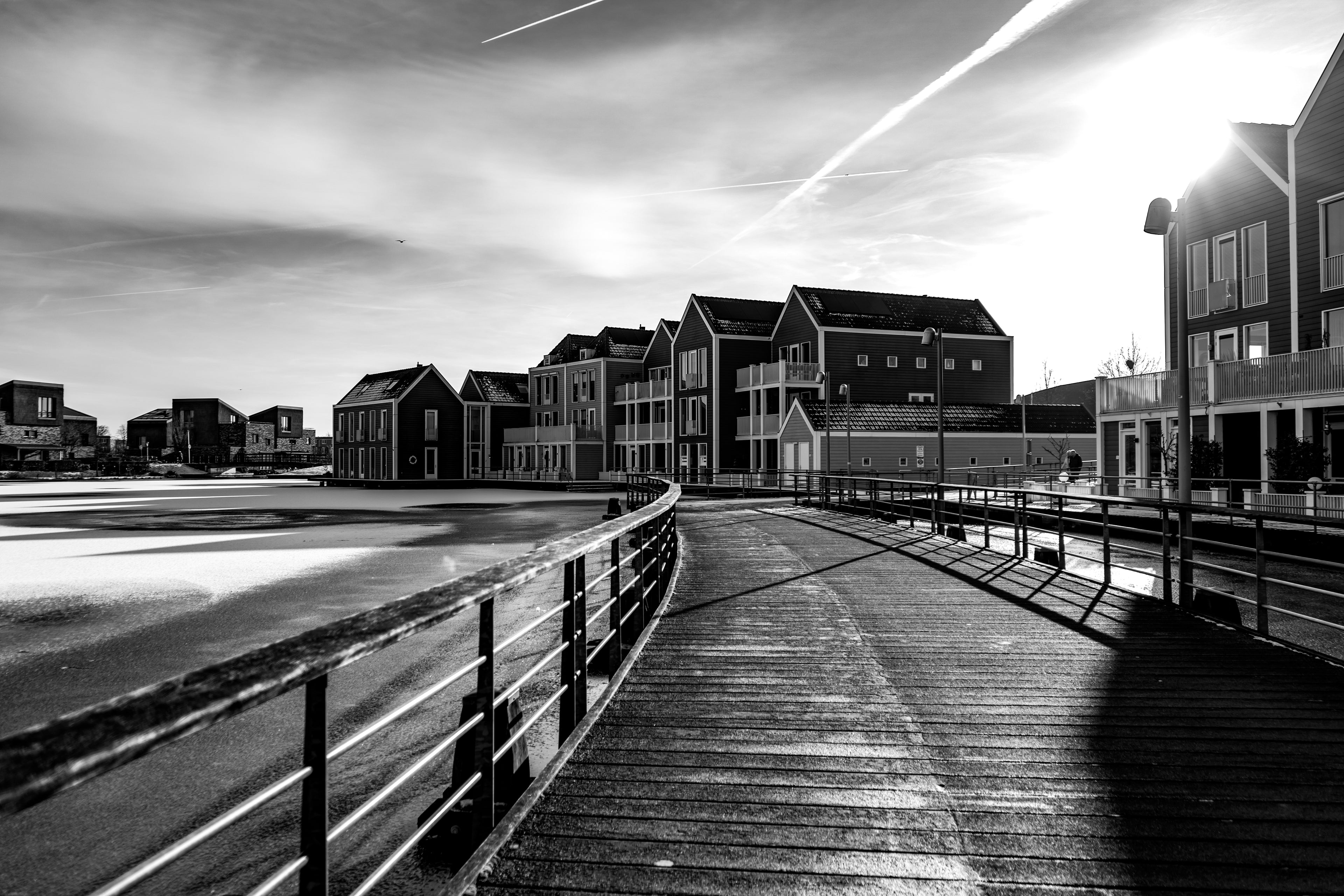 Black and white photograph of wooden waterfront houses and boardwalk in Houten reflecting calm urban architectural symmetry