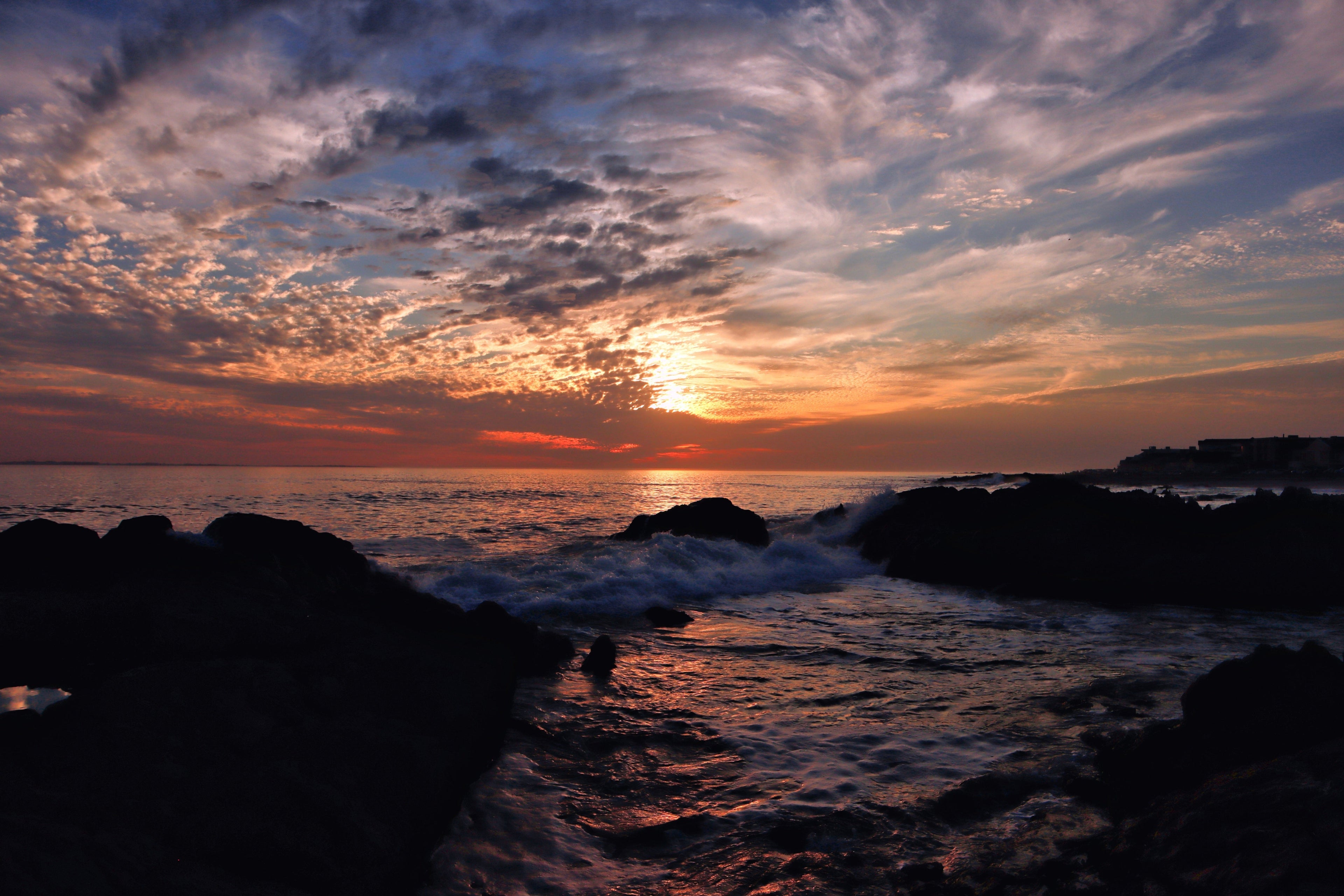 Dramatic ocean waves under moody sunset sky with textured clouds and fading golden light creating an atmospheric coastal seascape.