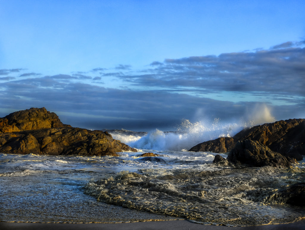 Ocean waves breaking over rocky shoreline at Yzerfontein on South Africa’s west coast under soft coastal light.